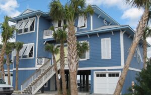 Home with pastel Bahama shutters providing tropical style and shade protection for windows.