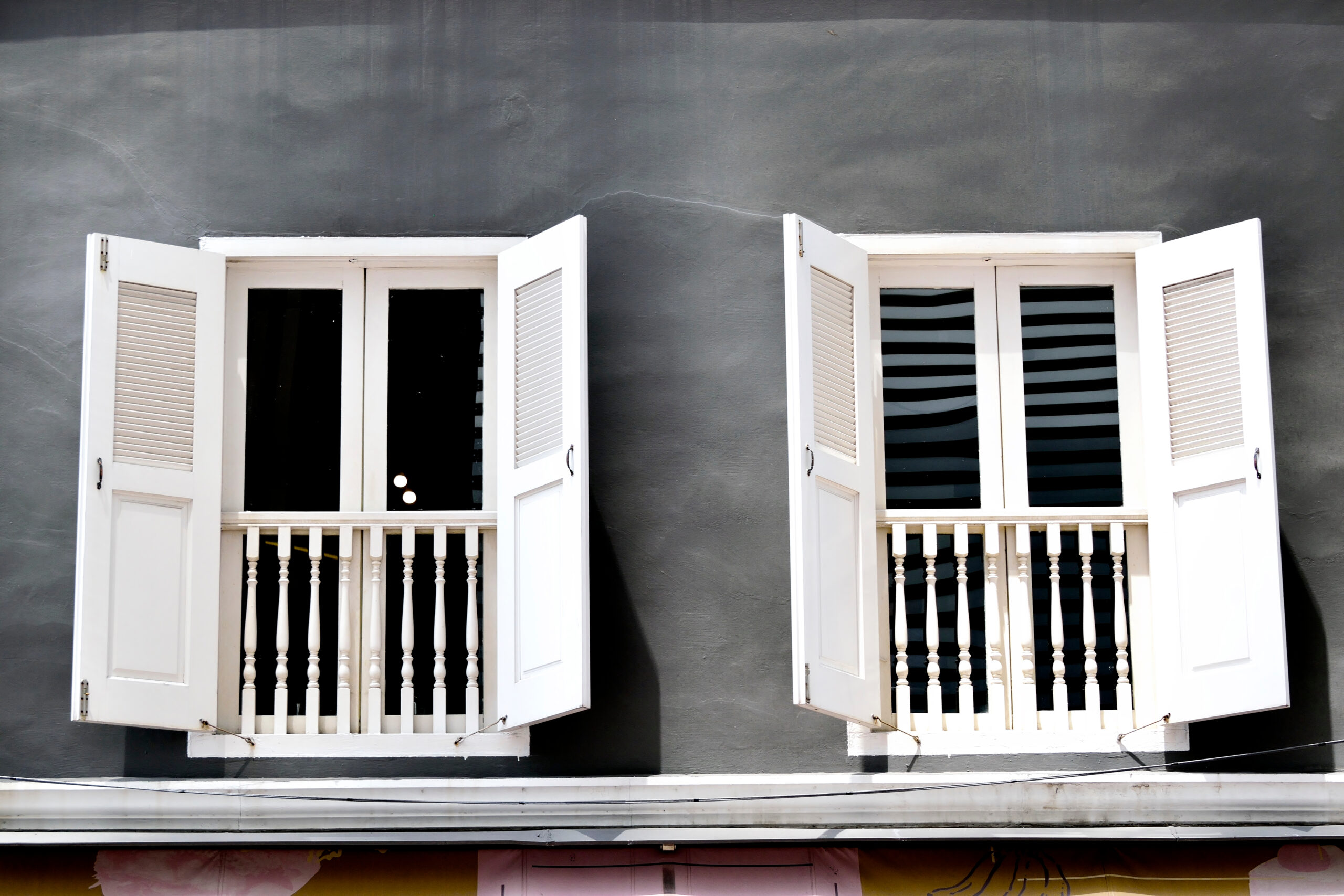 White exterior shutters on two windows of a gray building in Huntsville, AL, showcasing classic southern architectural style and curb appeal.
